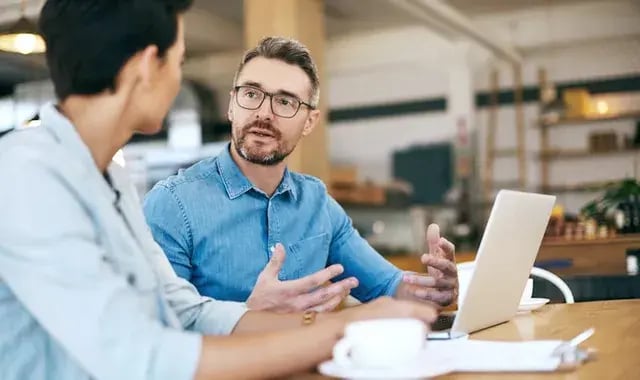 Man praat met andere man aan tafel