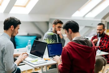 Vier mannen aan het werk op laptops