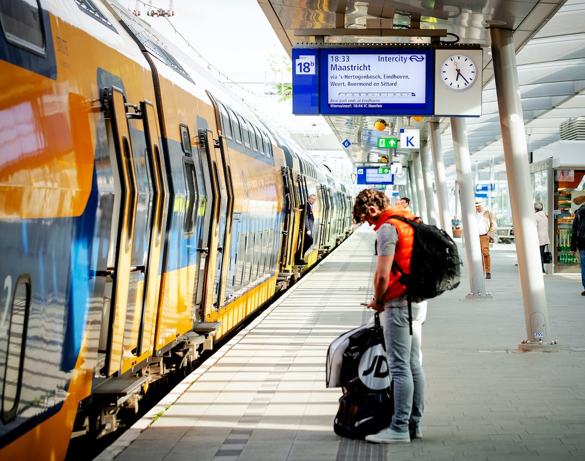 A train stopped at a train station platform, passengers standing on the platform