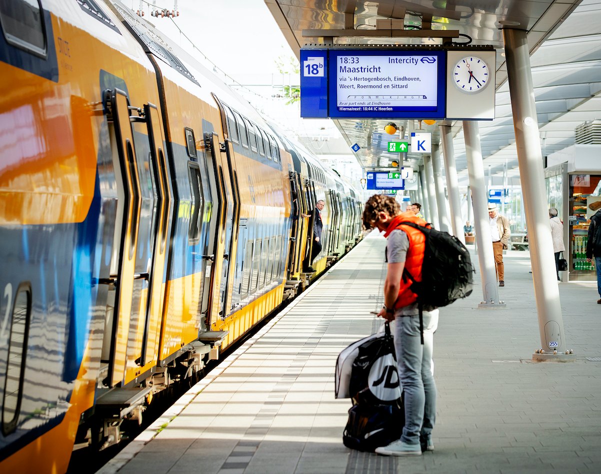 A train stopped at a train station platform, passengers standing on the platform