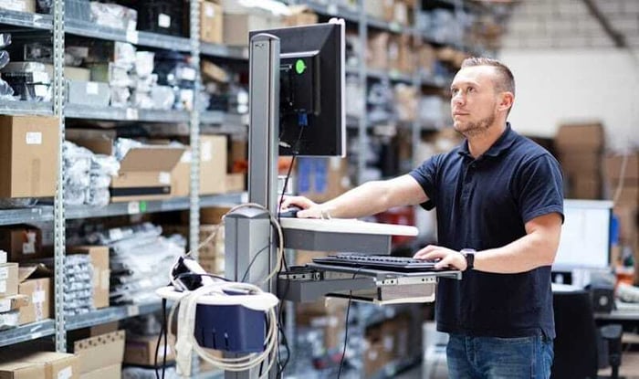 Mannelijke werknemer kijkt naar een computer in een loods.