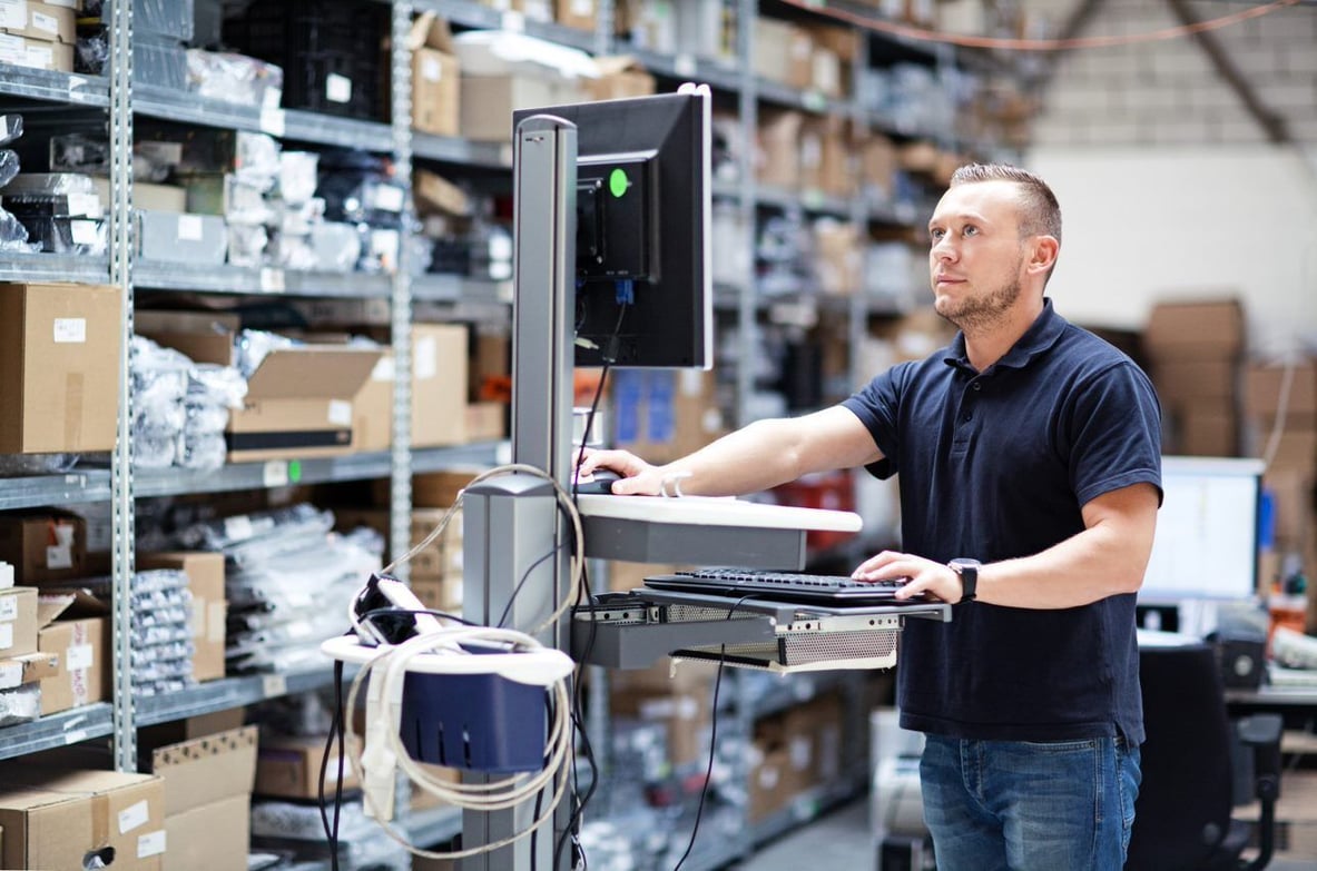 A man working in a warehouse on a desktop computer
