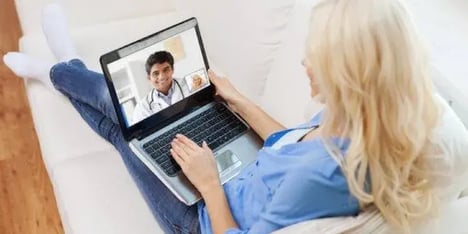 Vrouw op de bank bellend op laptop met arts