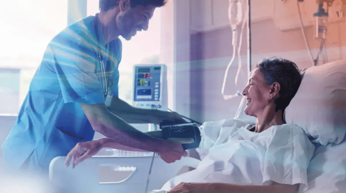 Verpleger die een hartslagmeter bij een vrouwelijke patiënt om de arm doet