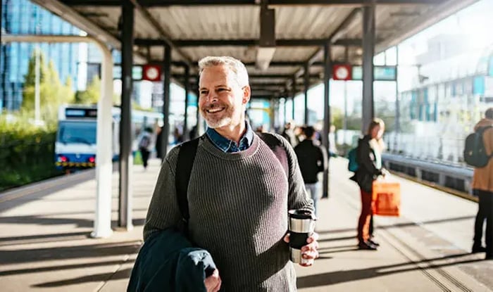 Reiziger op het spoor met koffie in zijn hand.