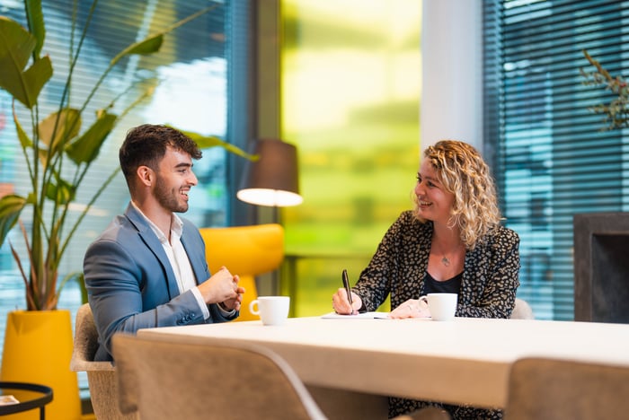 Twee lachende collega's in gesprek.
