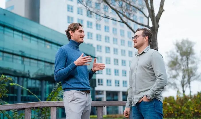 Two colleagues are standing outside of the office and are talking to each other.