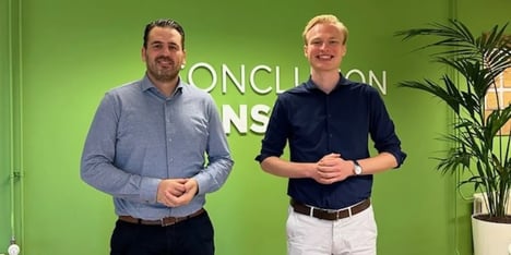 Twee mannen staan voor een groene muur