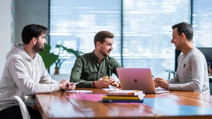 Collega's zitten aan een bureau te overleggen.
