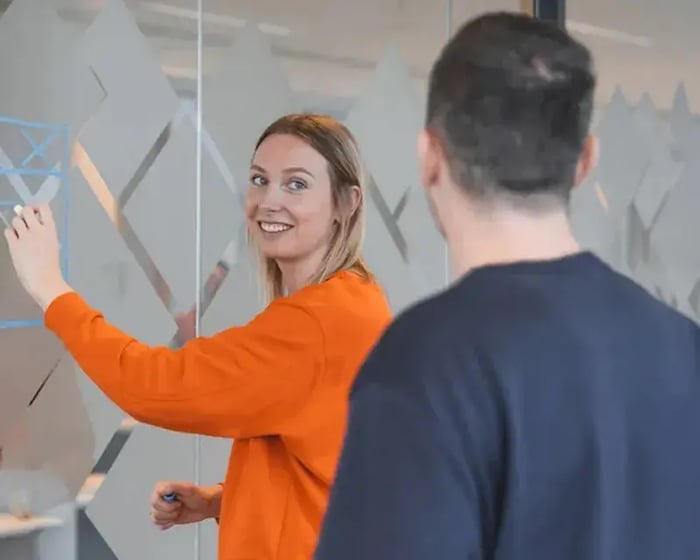 Vrouwelijke collega hangt post-its op een glazen wand.