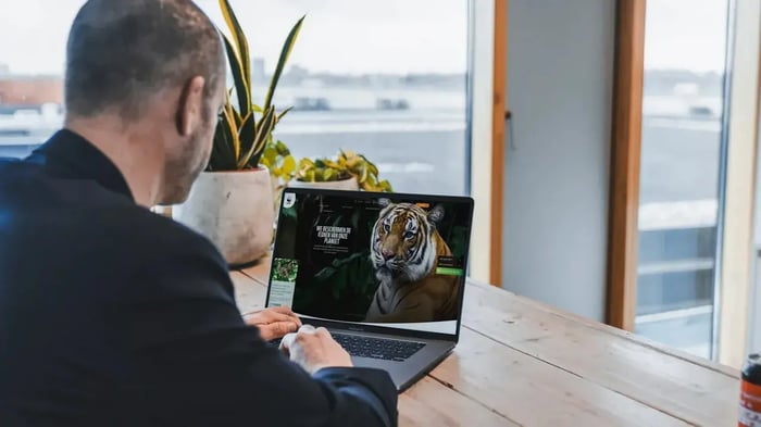 Man zit op laptop achter zijn bureau.