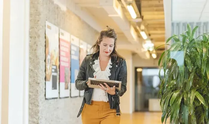 Vrouw kijkt al lopend op haar laptop.