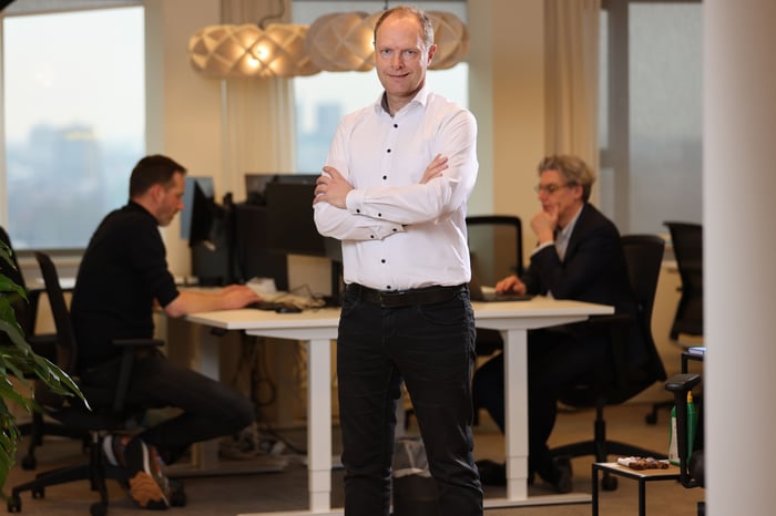 Een man die glimlachend met zijn armen over elkaar staat