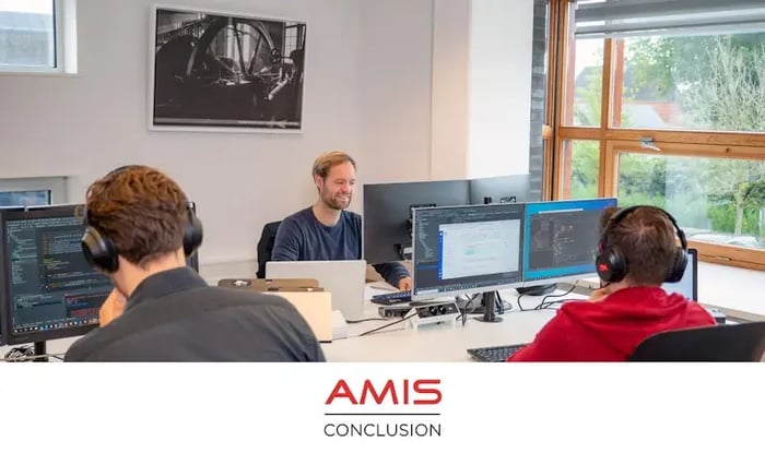 A male colleague is sitting behind computer screens.