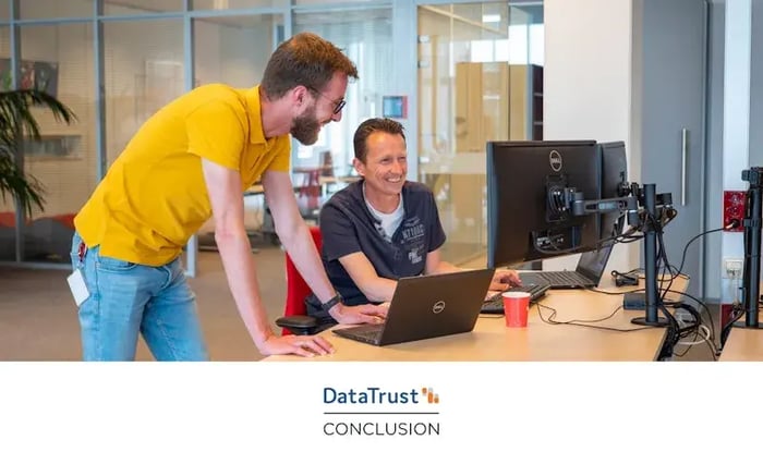 Two colleagues are smiling and looking at a computer screen.