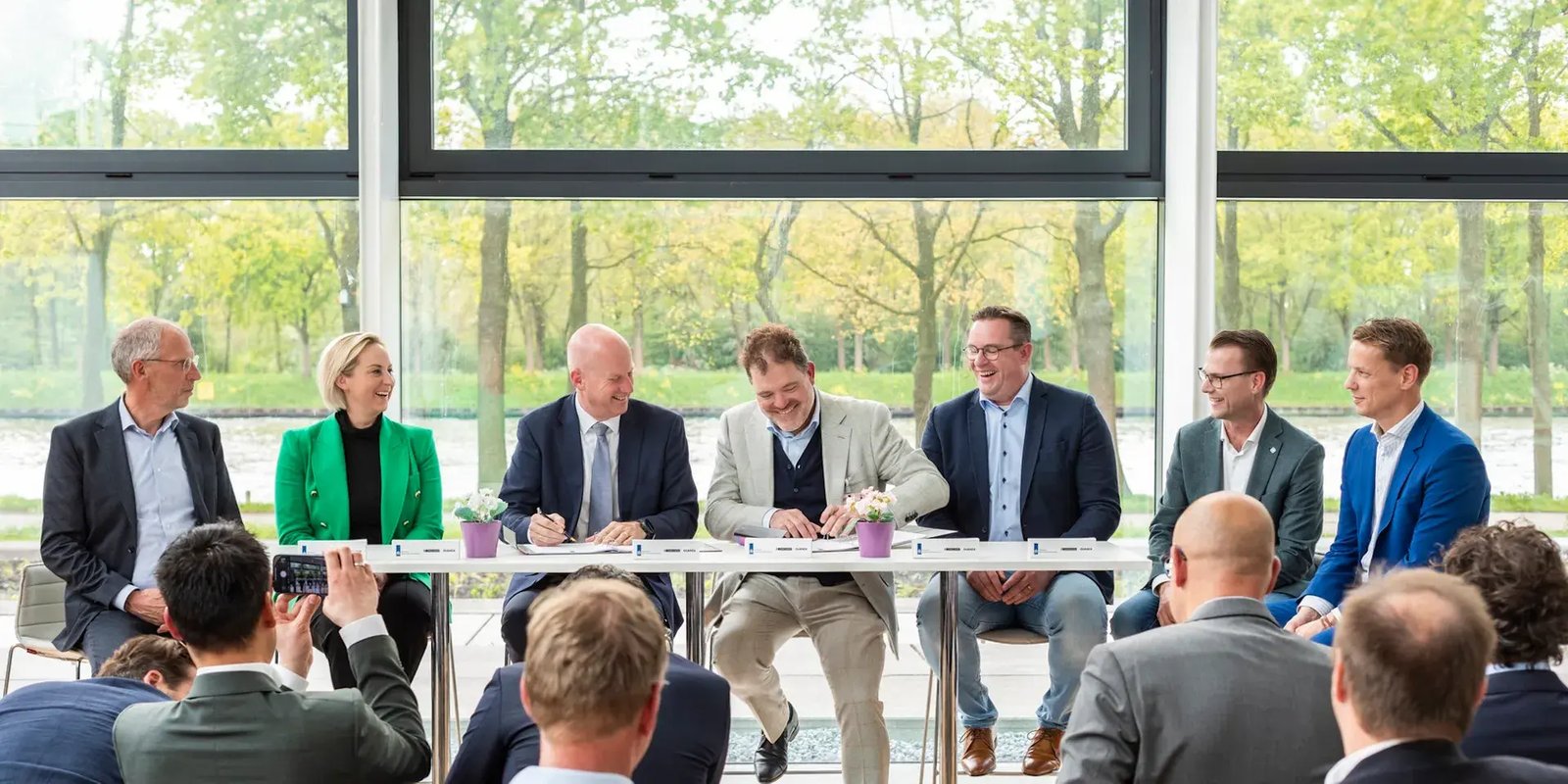 Lange tafel met daaraan medewerkers van Rijkswaterstaat, Quanza en Conclusion die overeenkomst tekenen