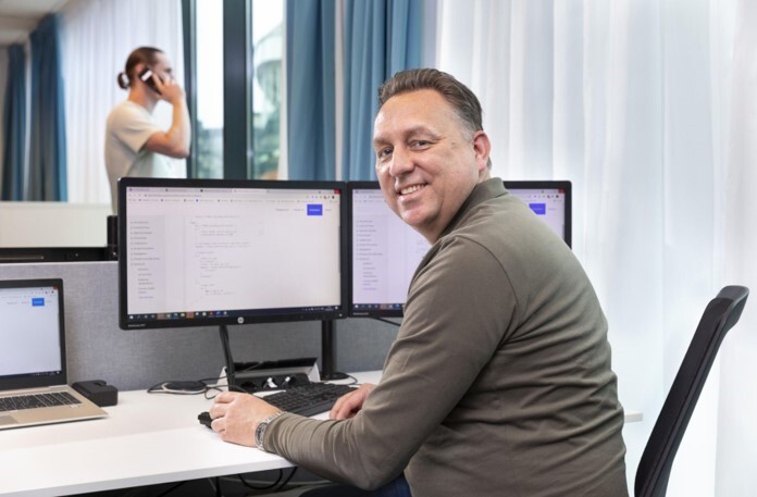 A man behind his desk smiling at the camera.