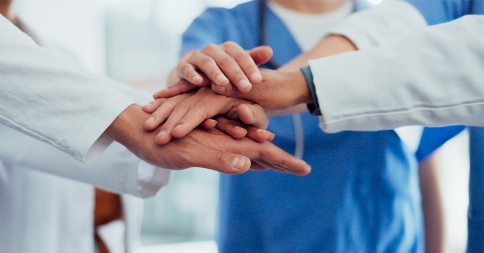 zorgmedewerkers die hun handen op elkaar stapelen