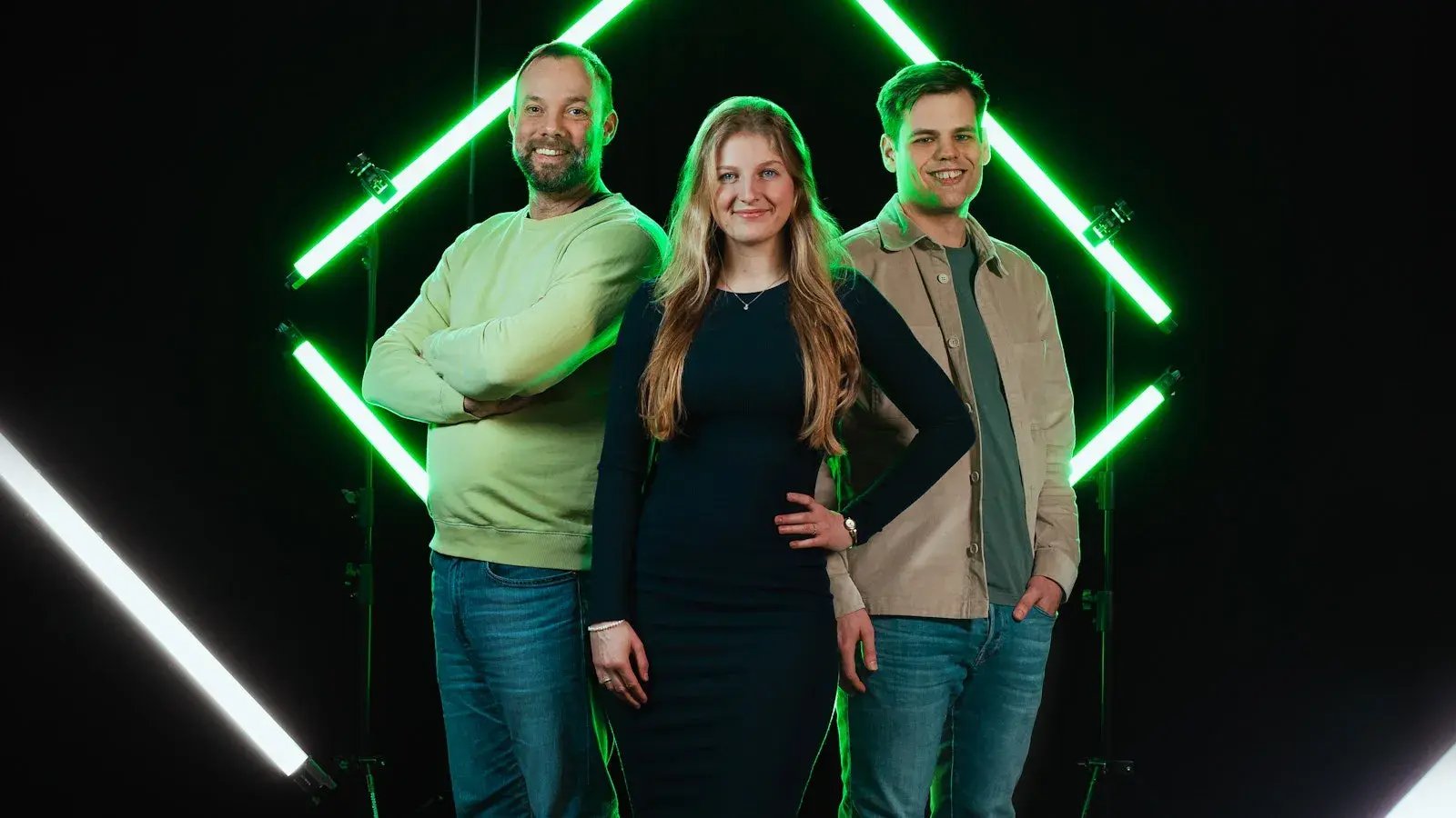 Drie medewerkers van Conclusion Integrations tegen een zwarte achtergrond met groene lichten