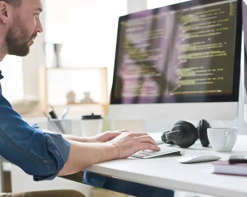 Man die code schrijft op groot beeldscherm