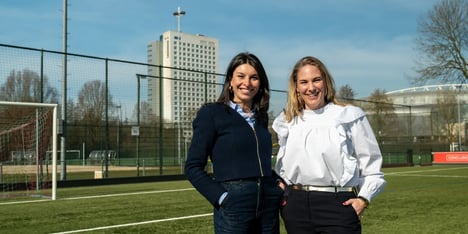 Two female colleagues from Conclusion are posing on a football field.