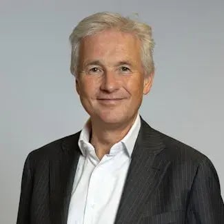 Retrato de Engbert Verkoren, um homem de cabelo grisalho, com uma camisa branca e um casaco preto, a sorrir.