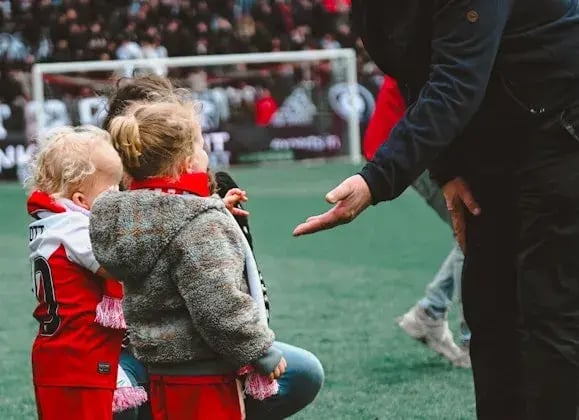Scott and a girlfriend of his are about to shake hands on the football field with a man.