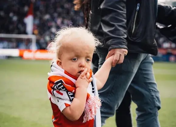 Scott houdt de hand van een man vast op het voetbaldveld van FC Utrecht.
