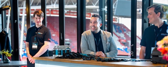 Collega's van Xforce bij een stand in het voetbalstadion.