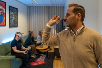 Alt-tekst: man gooit dartpijl terwijl anderen VR-bril gebruiken in ontspanningsruimte