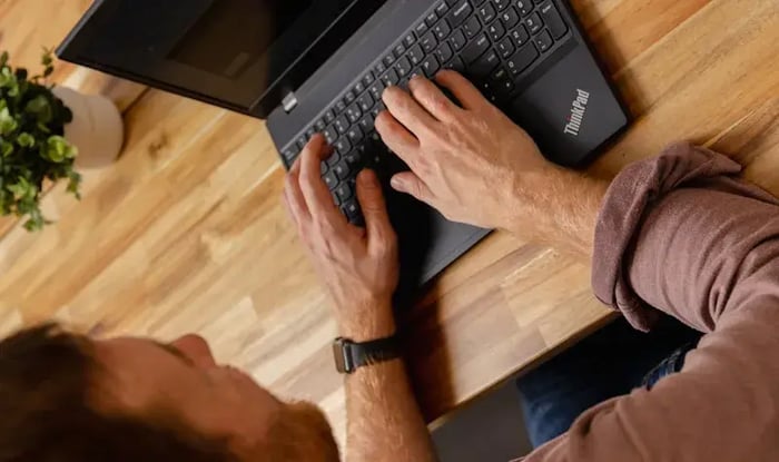 Man typt op een laptop.