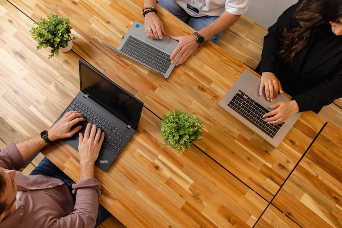 Drie collega's aan het werk met hun laptop.