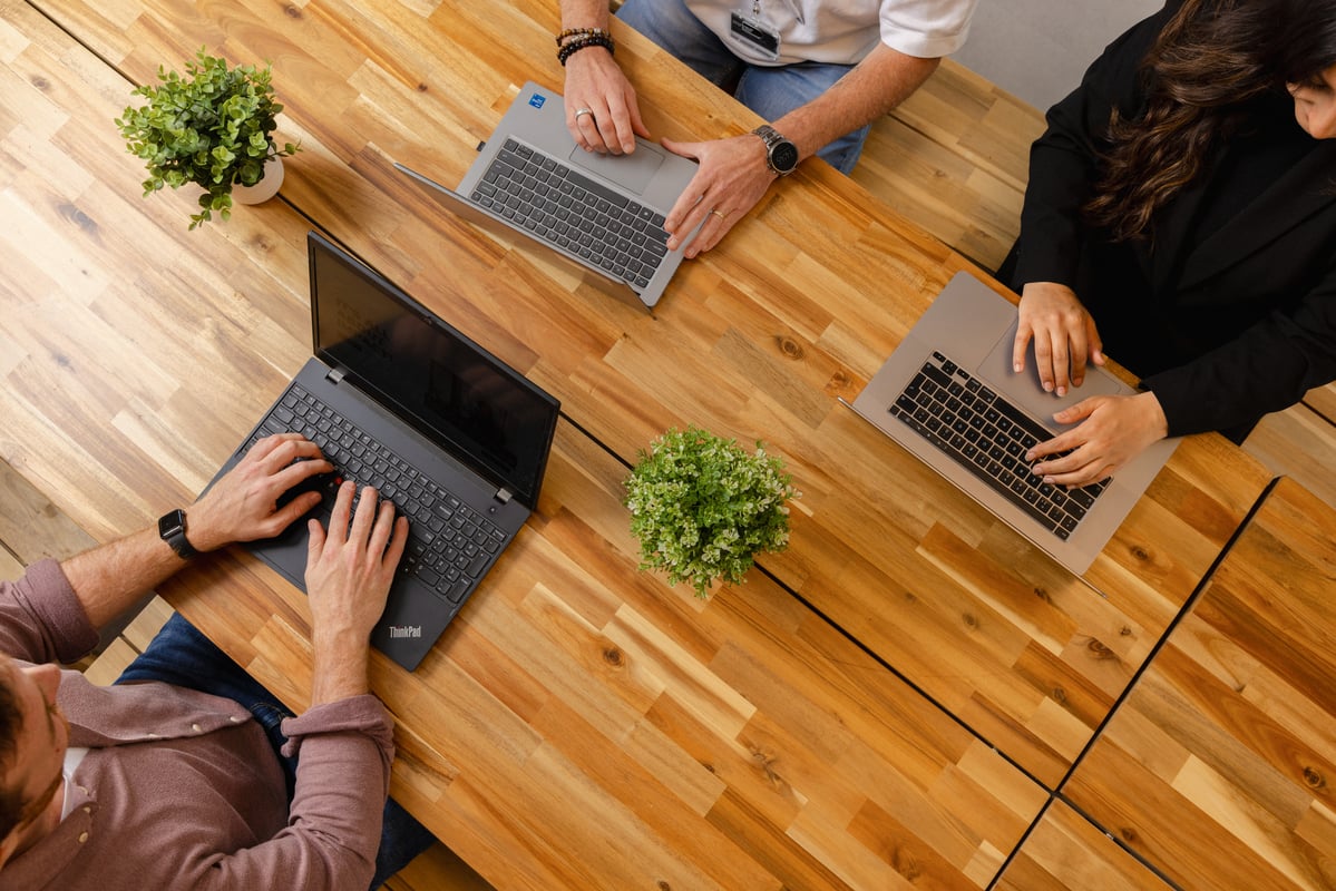 Drie collega's aan het werk met hun laptop.