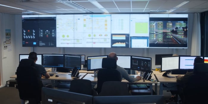 mannen achter meerdere beeldschermen