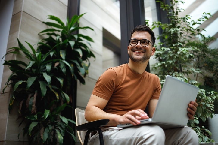 man zit lachend met laptop op schoot