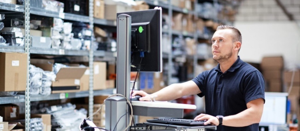 man in magazijn werkt op computer