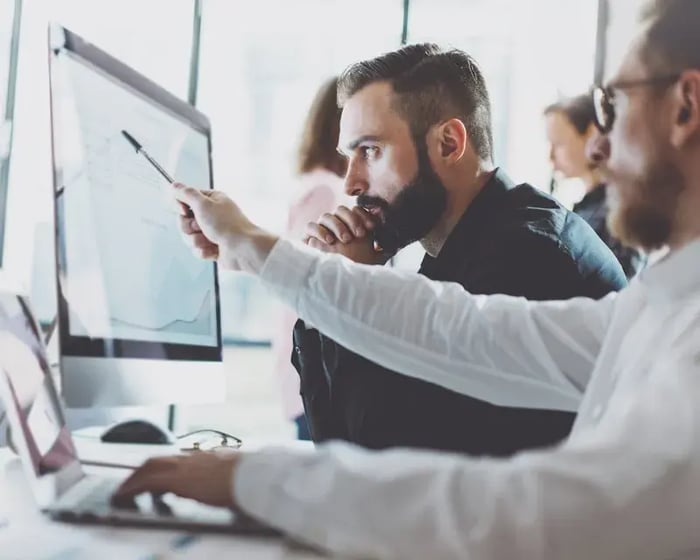Collegas wijzen naar een scherm