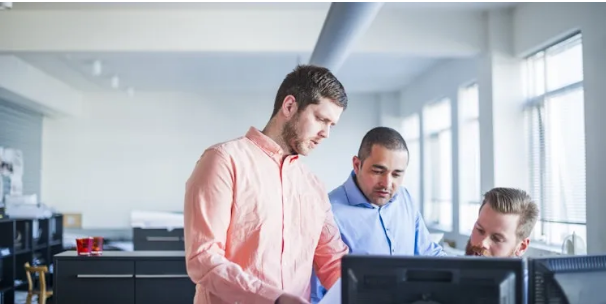 Drie collegas kijken naar een scherm