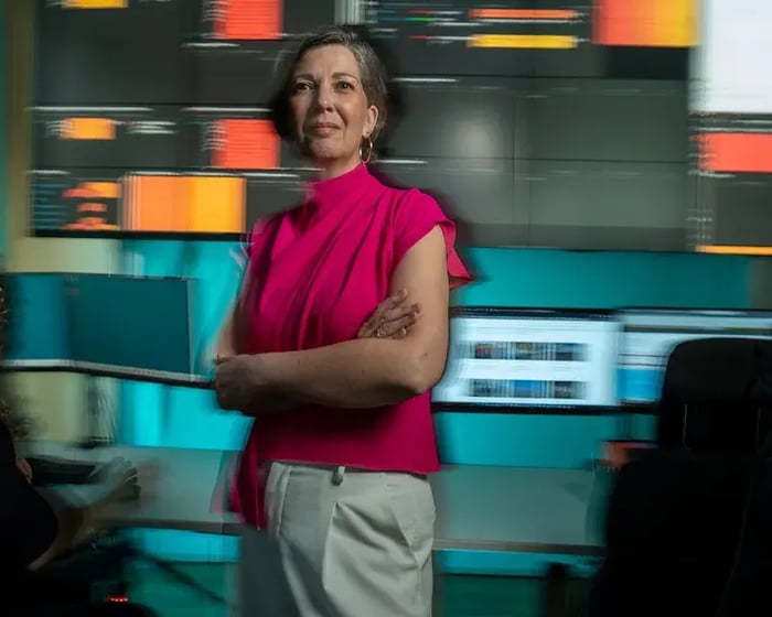 A woman is standing in front of a few screens.