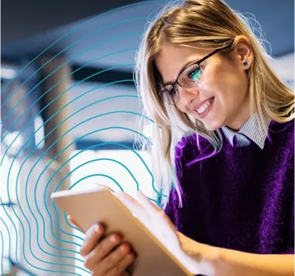 Vrouw met blond haar en een bril die lachend naar haar tablet kijkt