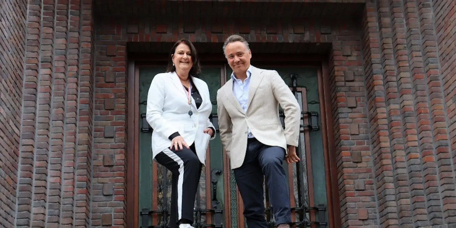 Two people stand proudly in front of a door