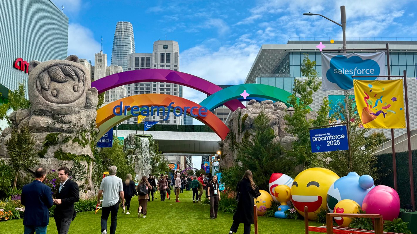 Dreamforce 2025 entree met regenboogboog, Salesforce Astro-beeld en emoji-ballonnen tussen de gebouwen van San Francisco.
