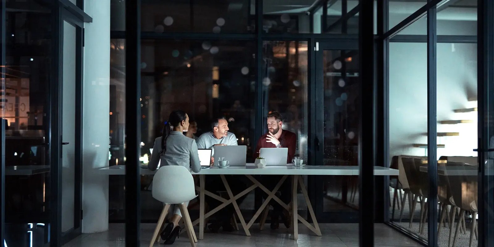 Drie mensen die werken met laptops aan een tafel