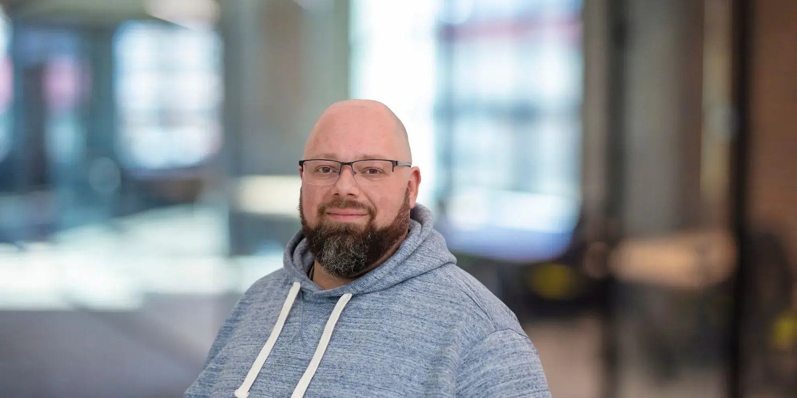 Man met bril zit en lacht