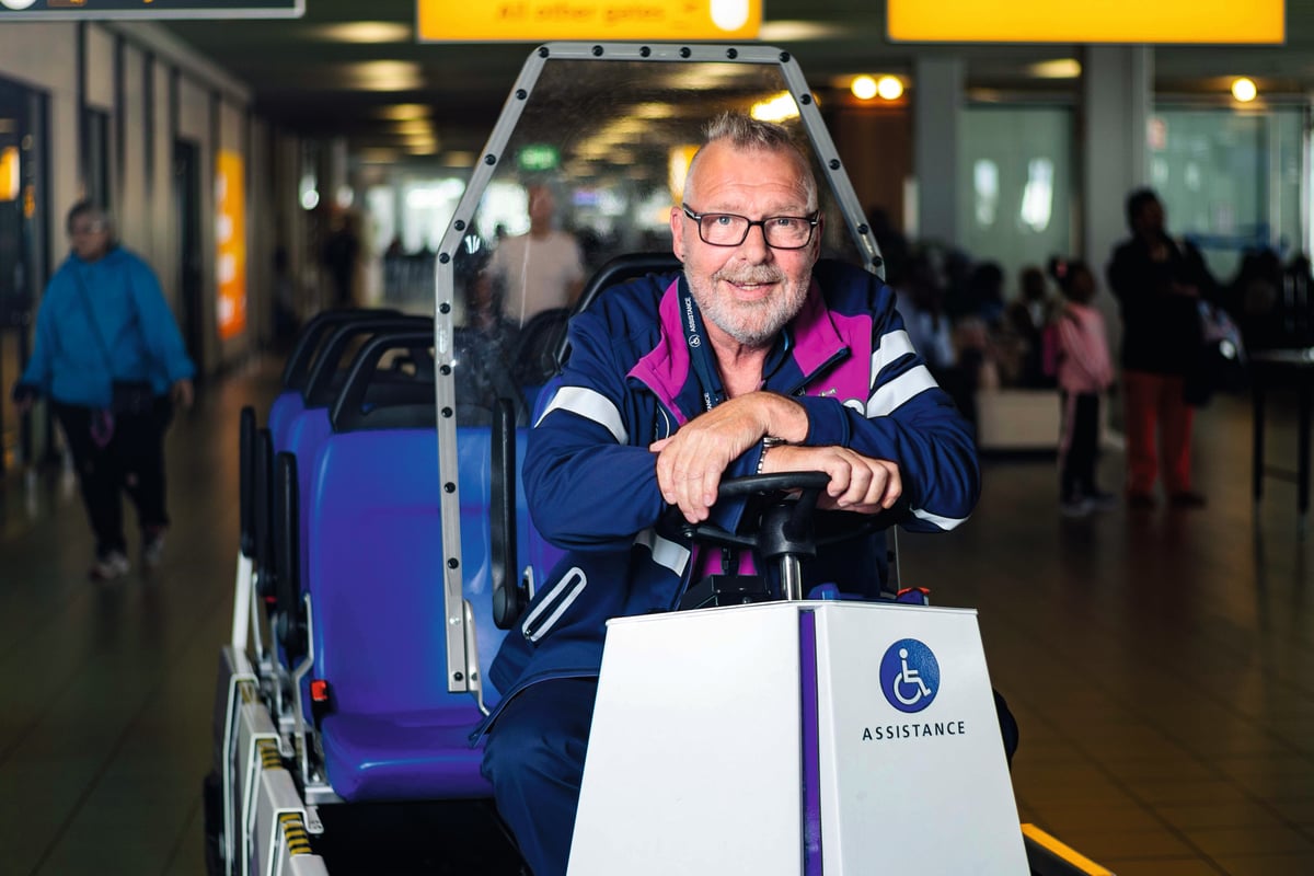 An airport employee posing on an airport caddy
