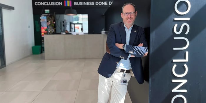 Witte man in nette kleding leunt tegen een muur met daarop de tekst 'Conclusion'