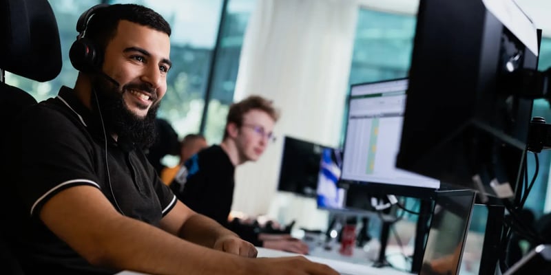 Twee collegas eentje met een headset kijken naar een scherm