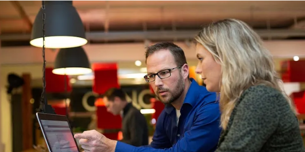 Twee collegas kijken naar een laptop