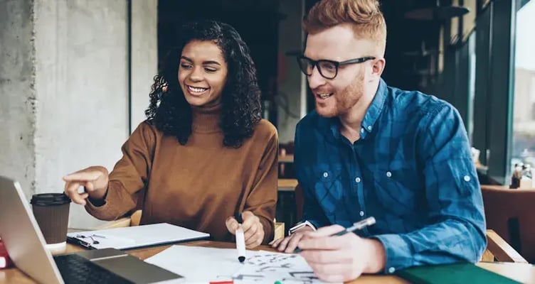 Twee collegas werken lachend aan een project
