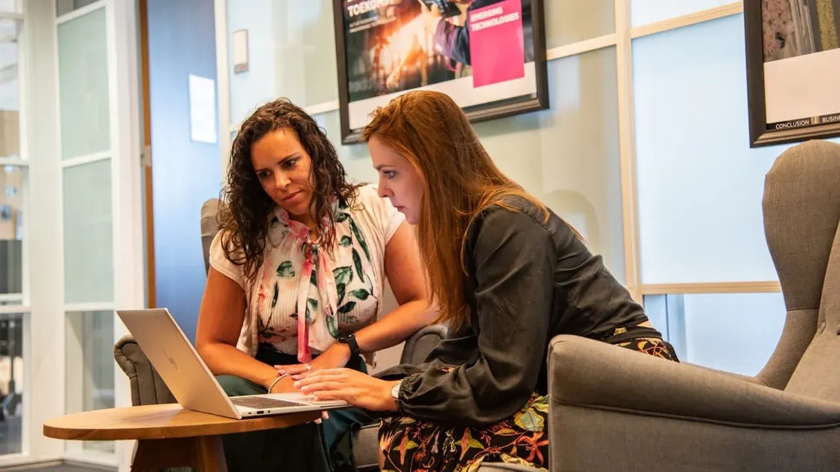 Twee dames in een kantoor kijken naar een laptop